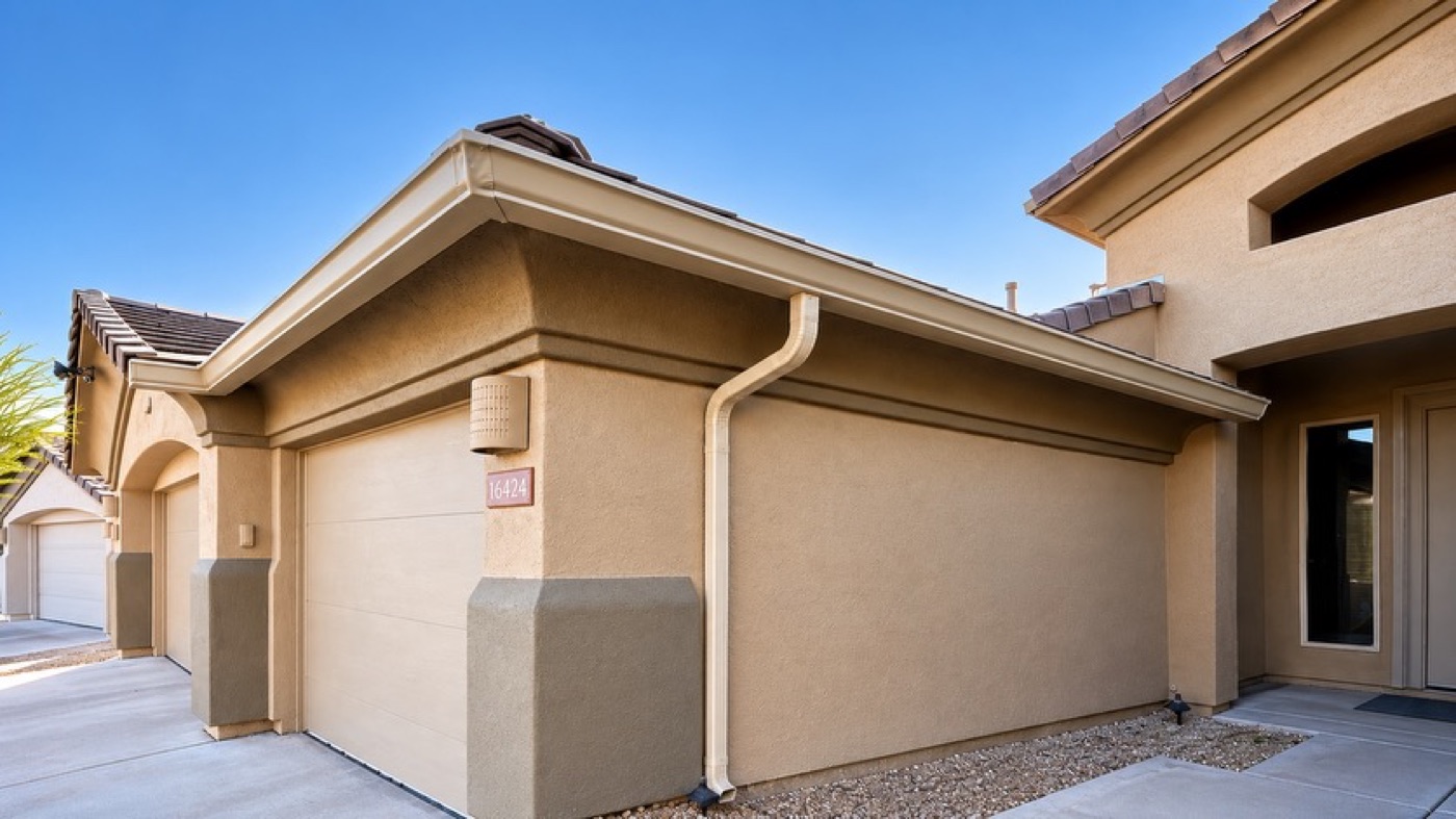 Tan seamless gutter and downspout colour-matched to stucco on an Arizona garage elevation