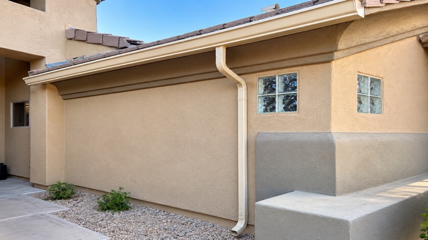 Tan seamless gutter along a stucco elevation with glass block windows, Arizona