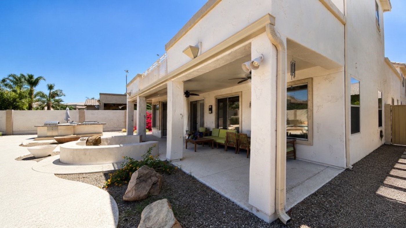 Downspout on a two-storey stucco home above a pool patio and outdoor kitchen, Arizona